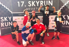 Jugendliche mit Medaillen stehen vor der Werbewand des 17. SkyRun in Frankfurt.