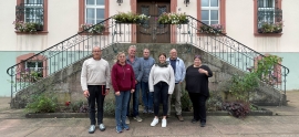 7 Frauen und Männer stehen vor einer Eingangstreppe