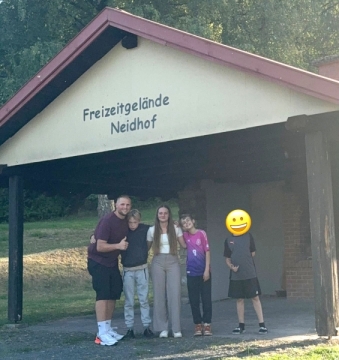Vier Jugendliche und ein erwachsener Betreuer stehen vor einem Gebäude mit AUfschrift "Freizeitgelände Neidhof"